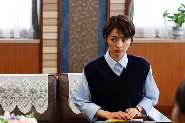 A female character from "To The Future 10 Count" sits, looking serious indoors.