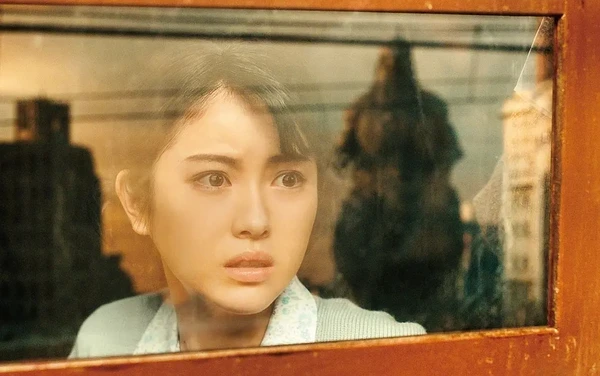 Woman staring through window with Godzilla shadow in Godzilla-1.0